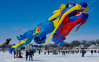 A group of people gathered in a snow-covered field preparing inflatable floats for a parade.