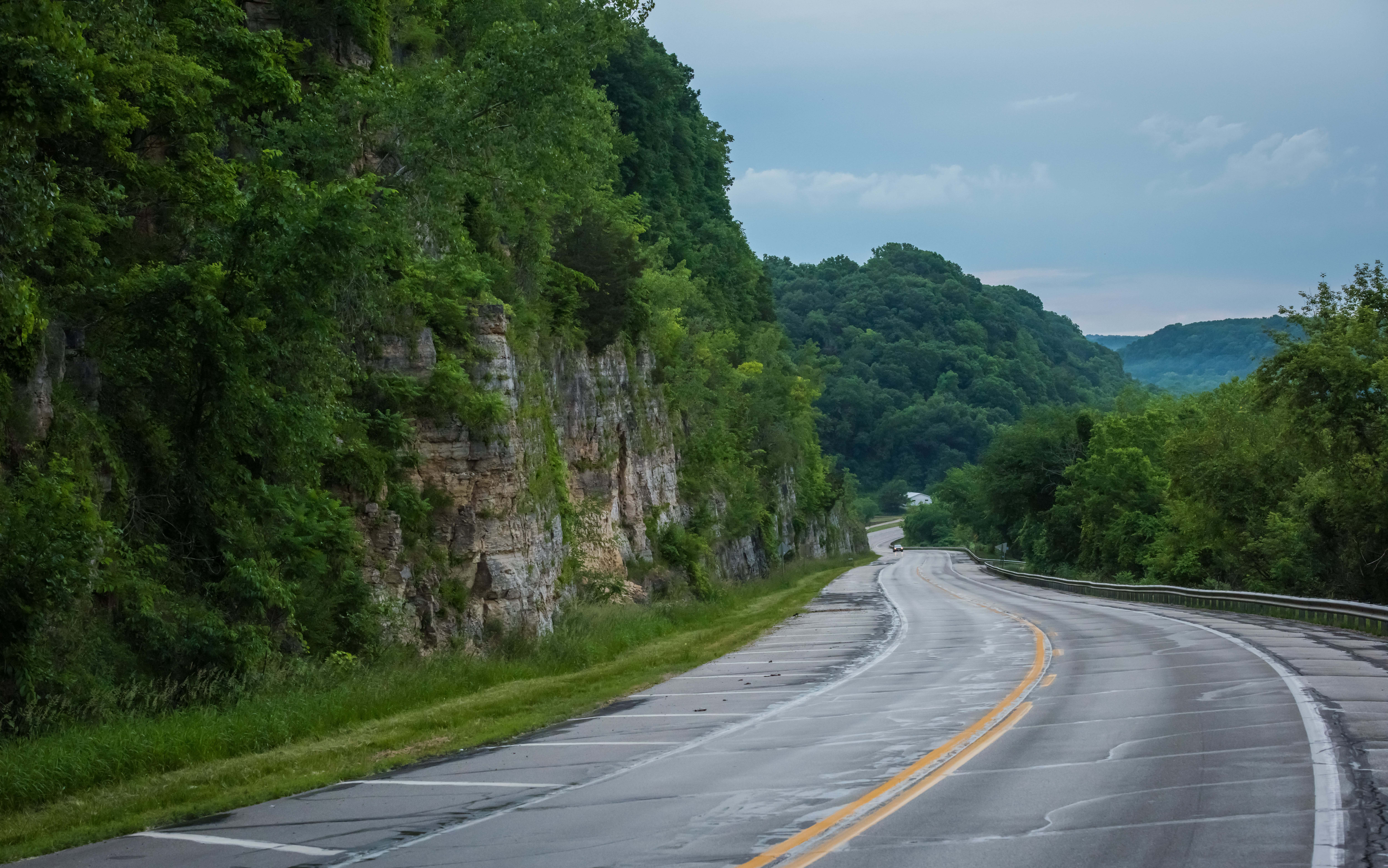 A paved road cuts through green-covered bluffs.